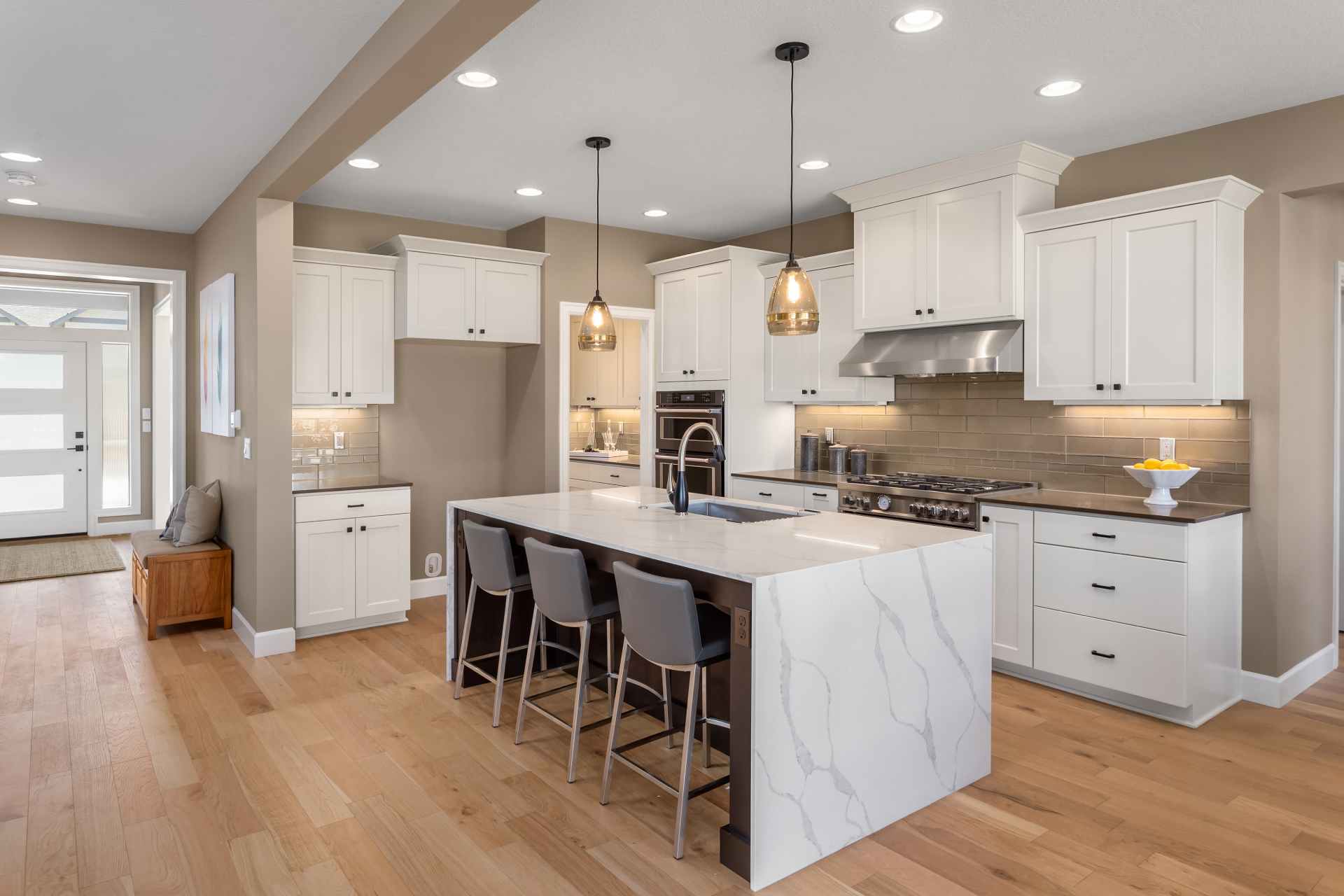 A kitchen with white cabinets and wooden floors.